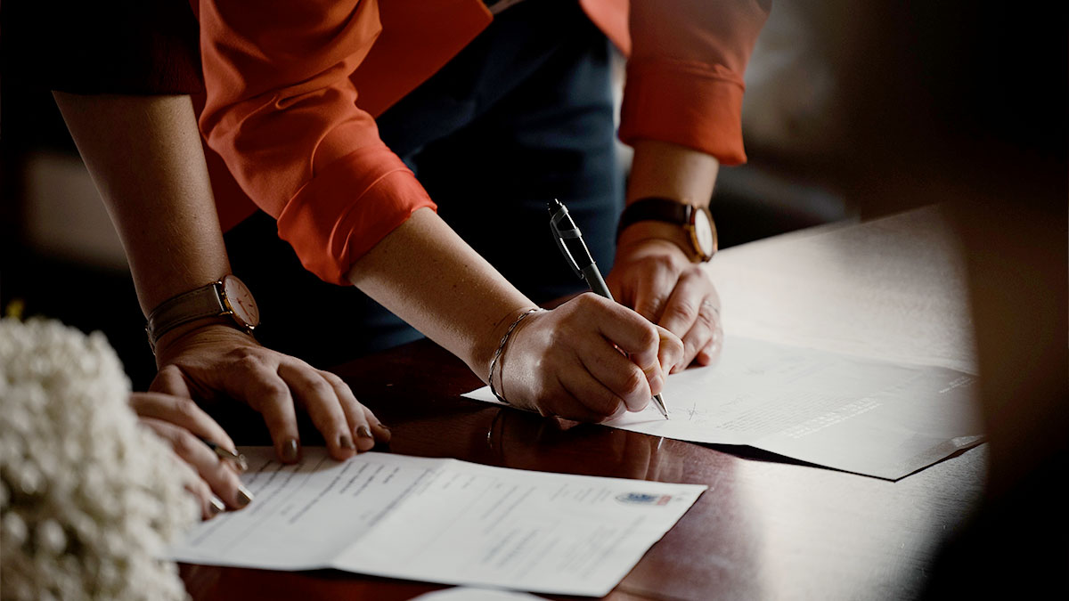 Two people stand over a desk reviewing papers