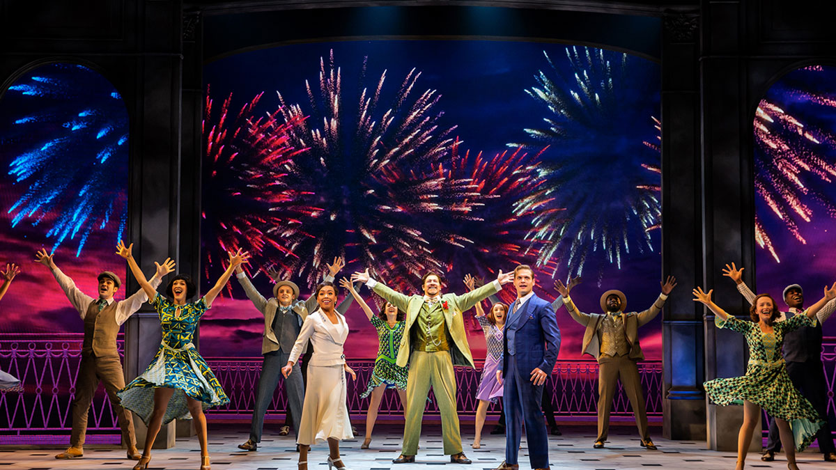 Performers posing in front of a colorful backdrop of fireworks